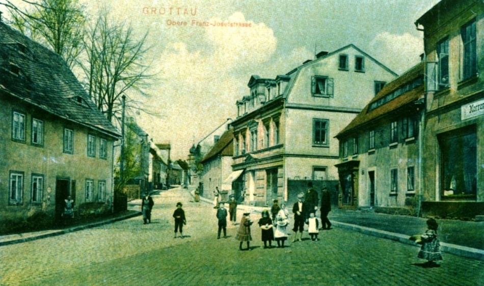 Typické prorůstání straší zástavby venkovského charakteru (okapově orientované domy v pravé a levé části snímku) historizující městskou zástavbou (dům čp. 261). Ulice 1. máje roku 1909